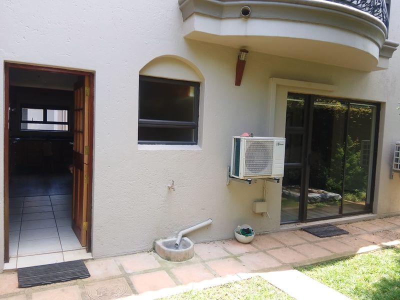 Rear exterior view showing a tiled patio area, sliding glass doors, timber door, and wall-mounted air conditioning unit.