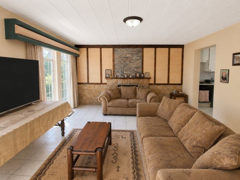 Spacious living room featuring a stone fireplace, timber wall paneling, tiled flooring, and direct access to the outdoors through sliding glass doors.