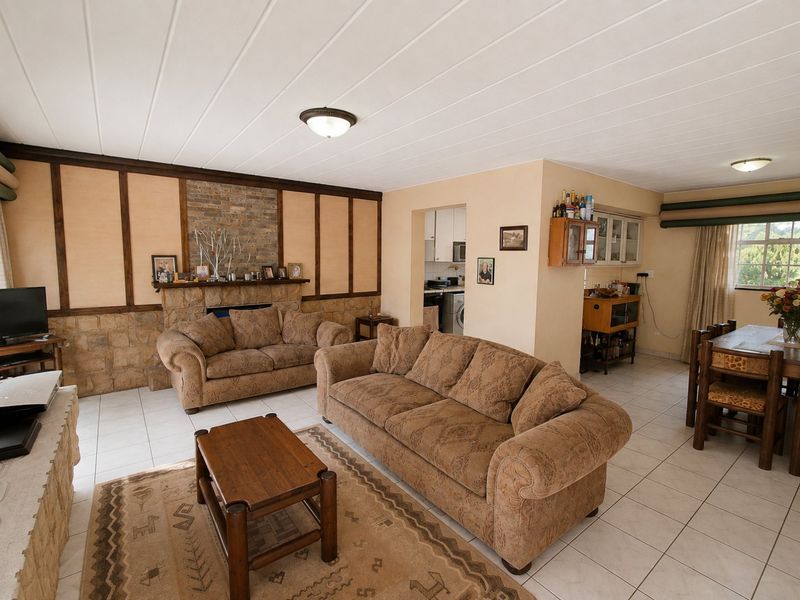 Spacious open-plan living and dining area featuring a stone fireplace, tiled flooring, and neutral wall finishes, offering a functional layout for family living.