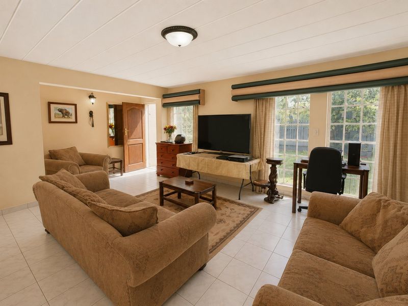 A spacious living room featuring tiled flooring, a paneled ceiling, and large windows that provide ample natural light.