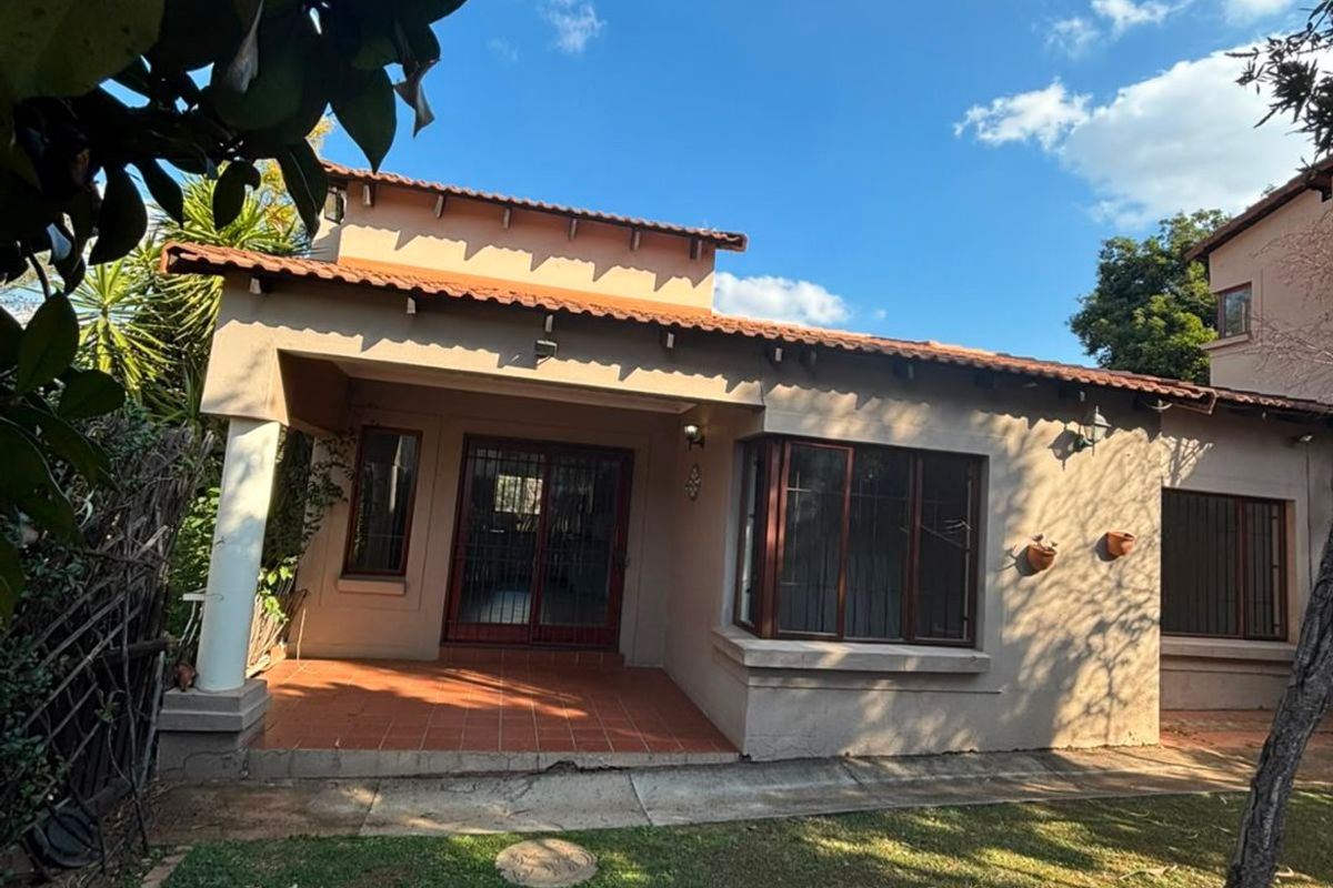 Rear view of the house featuring a covered terracotta tiled patio, bay window, and a landscaped garden with a stone pathway.