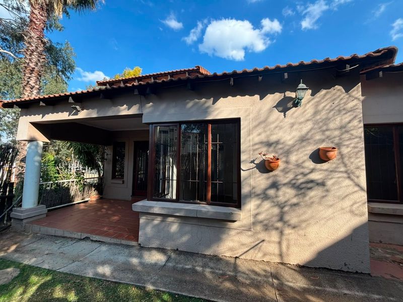 A rear view of the house featuring a covered patio with terracotta flooring, a bay window, and a classic tiled roof.