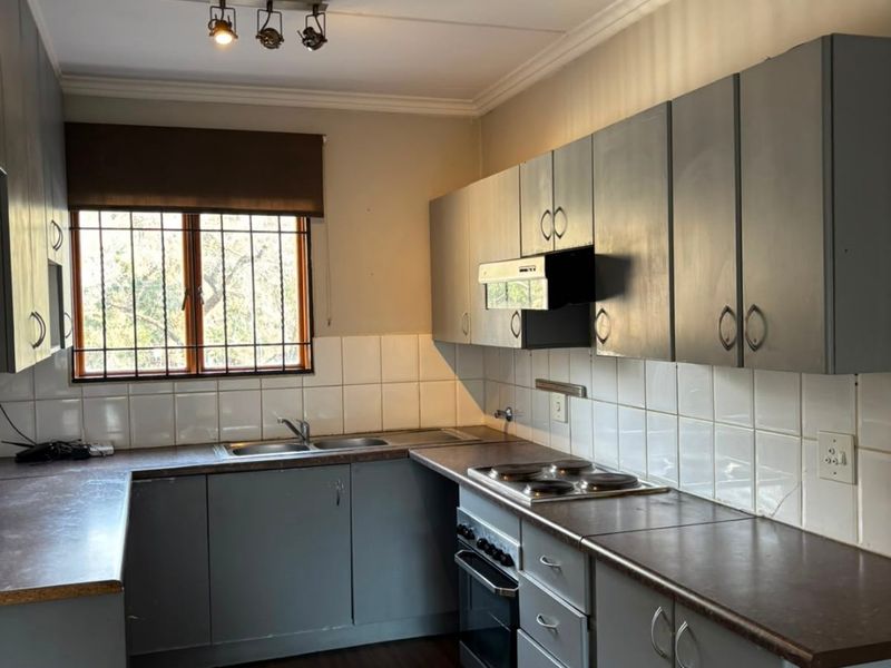 Functional kitchen featuring grey built-in cabinetry, laminate countertops, tiled splashbacks, and integrated electric cooking appliances.