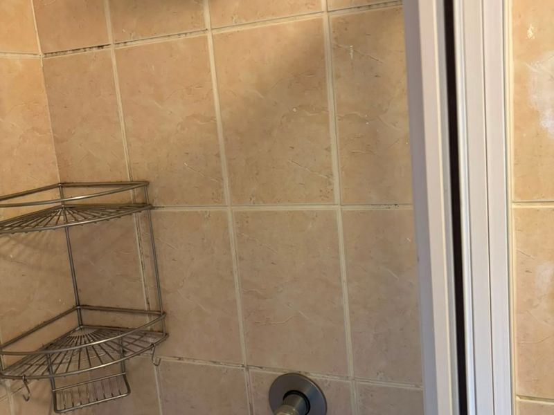 A shower stall featuring beige wall tiles, a modern shower head, and a single-lever mixer tap.