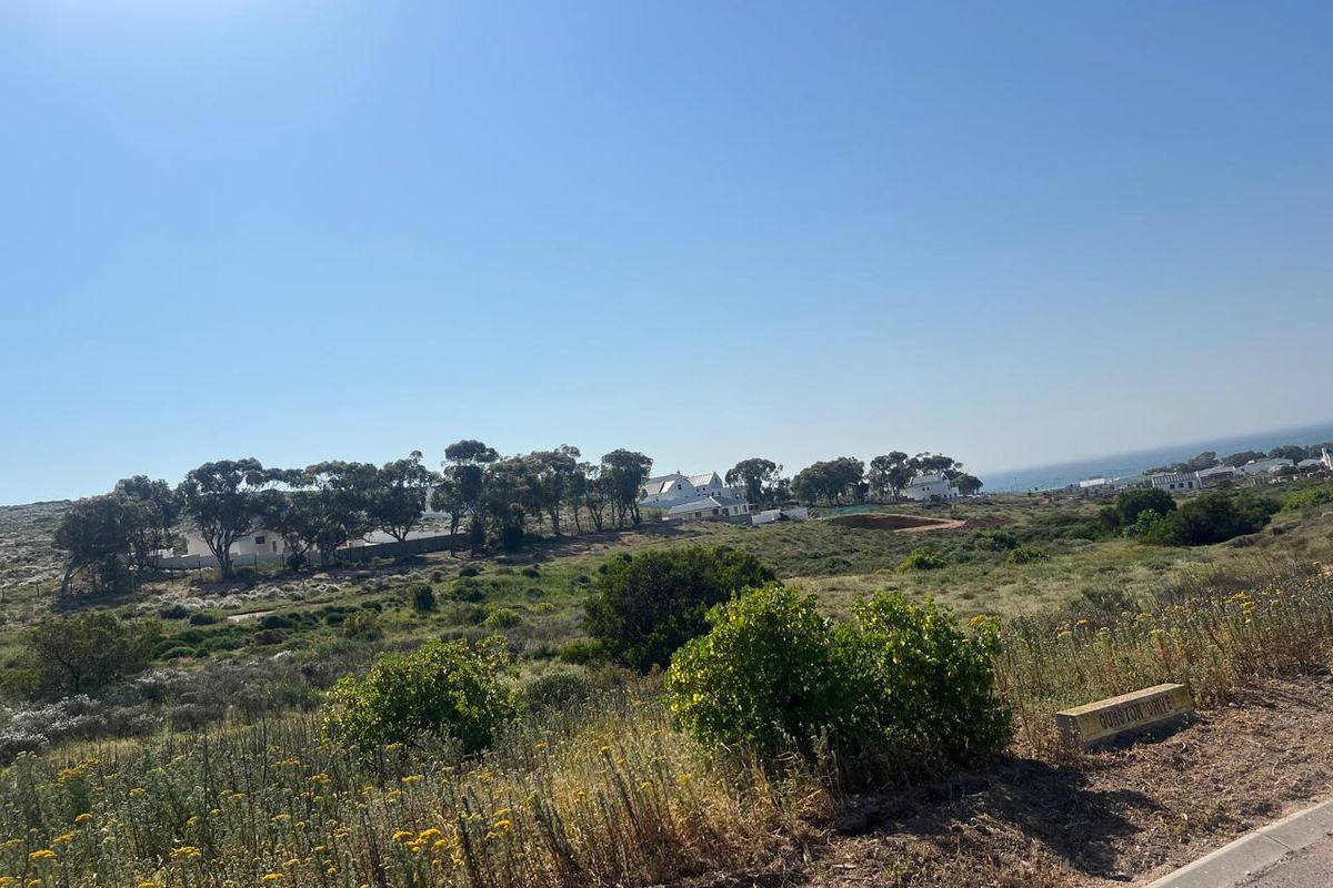 A scenic view of the vacant residential land featuring natural coastal vegetation and surrounding neighborhood landscape.