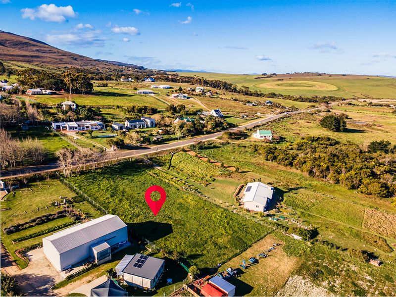 Aerial view of a vacant residential plot situated in a rural landscape with surrounding infrastructure and access roads.