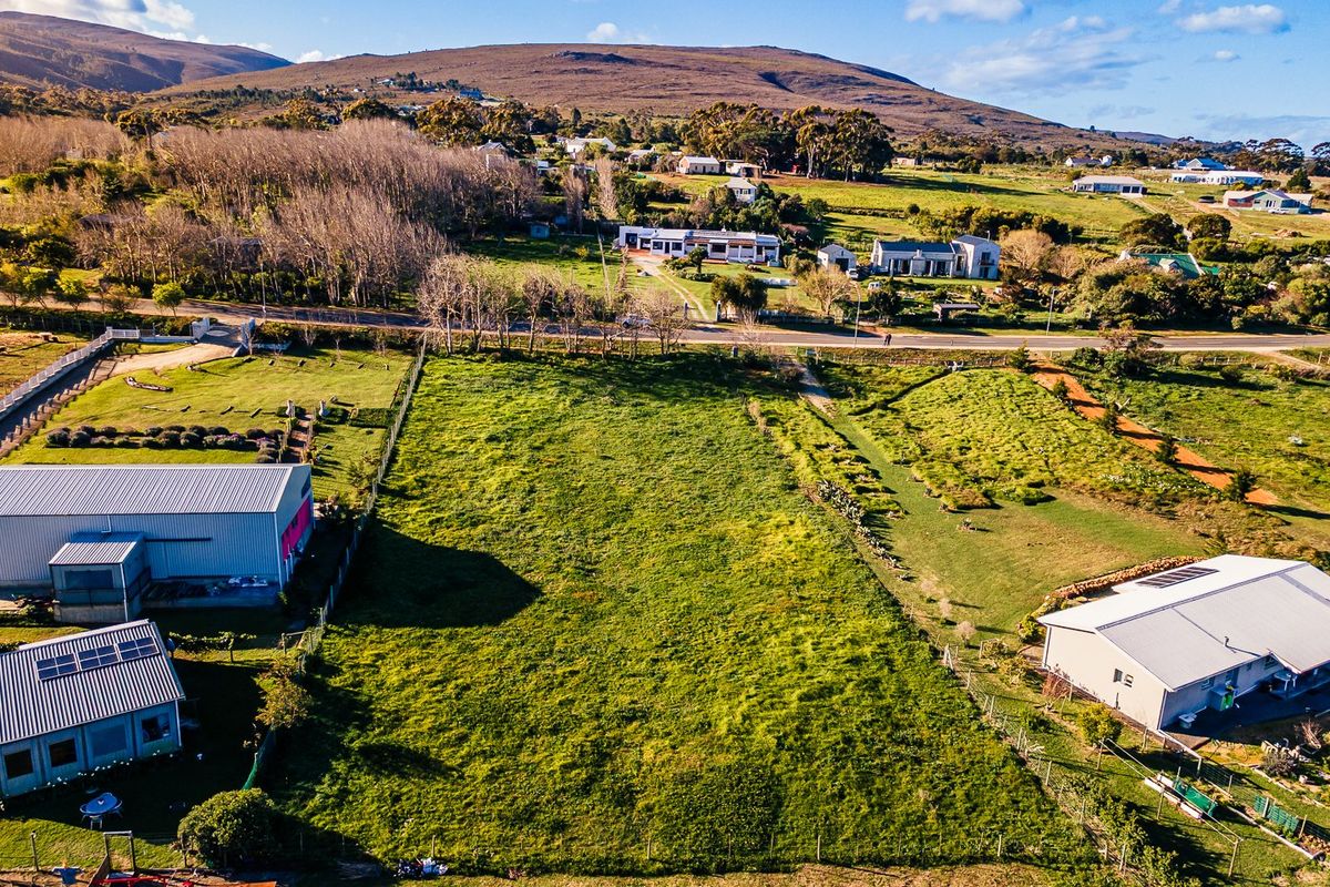 An aerial view of a vacant residential plot featuring open grassland, established boundary fencing, and surrounding rural landscape.