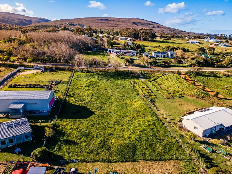 An aerial view of a vacant residential plot featuring open grassland, established boundary fencing, and surrounding rural landscape.