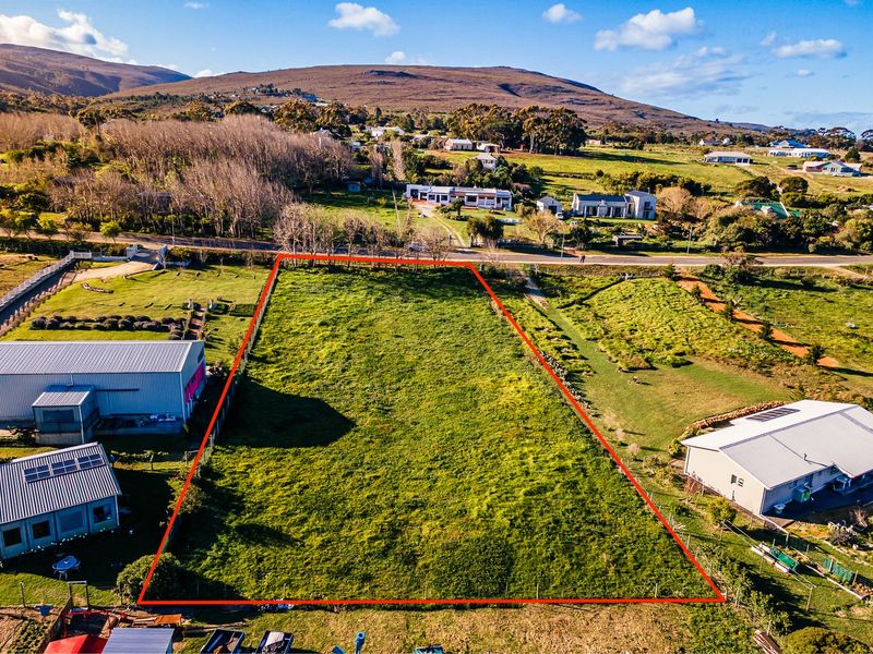 An aerial view of a vacant residential plot of land, clearly outlined in red, situated in a semi-rural neighborhood setting.