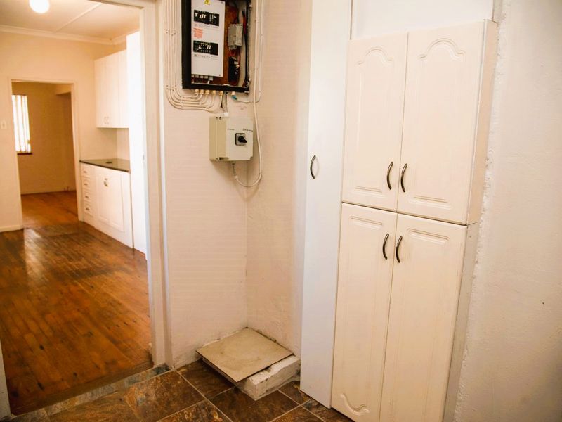 Utility area featuring built-in storage cabinetry and an exposed electrical distribution board, with a transition between tiled and timber flooring.