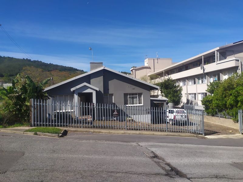 Front exterior view of a detached house featuring a gabled roof, chimney, and secure steel palisade fencing along the street boundary.