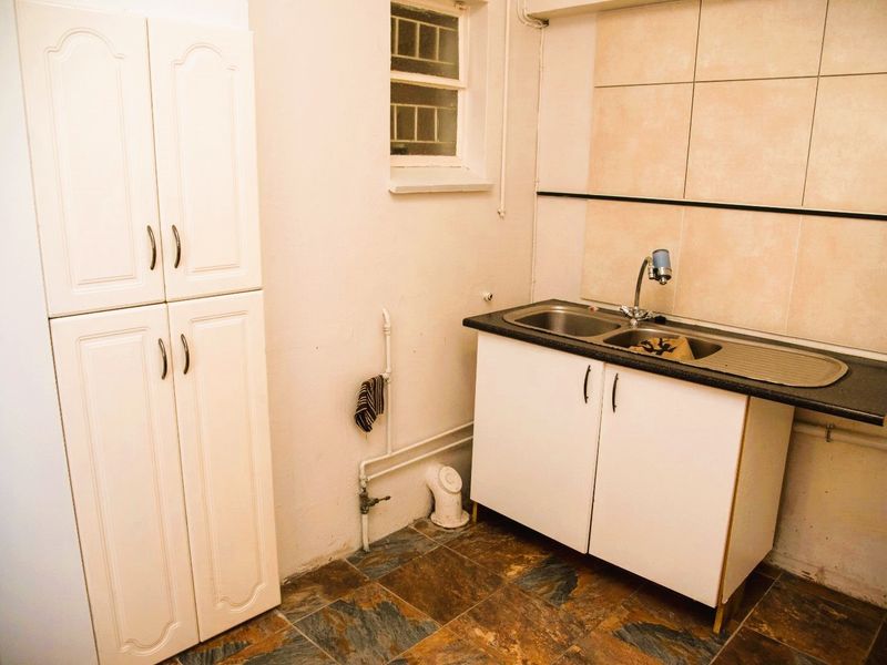 A functional scullery or utility area featuring built-in cabinetry, a double sink, and tiled splashbacks, providing practical space for wash-up and storage.