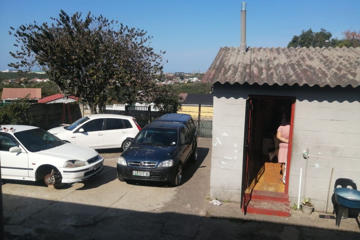 Exterior view of a rear outbuilding featuring a corrugated roof and concrete block construction, situated on a paved driveway area.