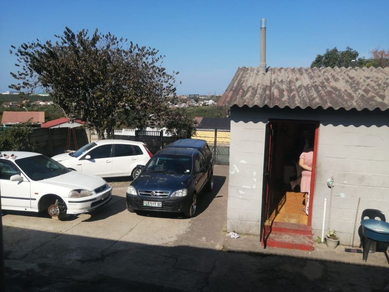 Exterior view of a rear outbuilding featuring a corrugated roof and concrete block construction, situated on a paved driveway area.