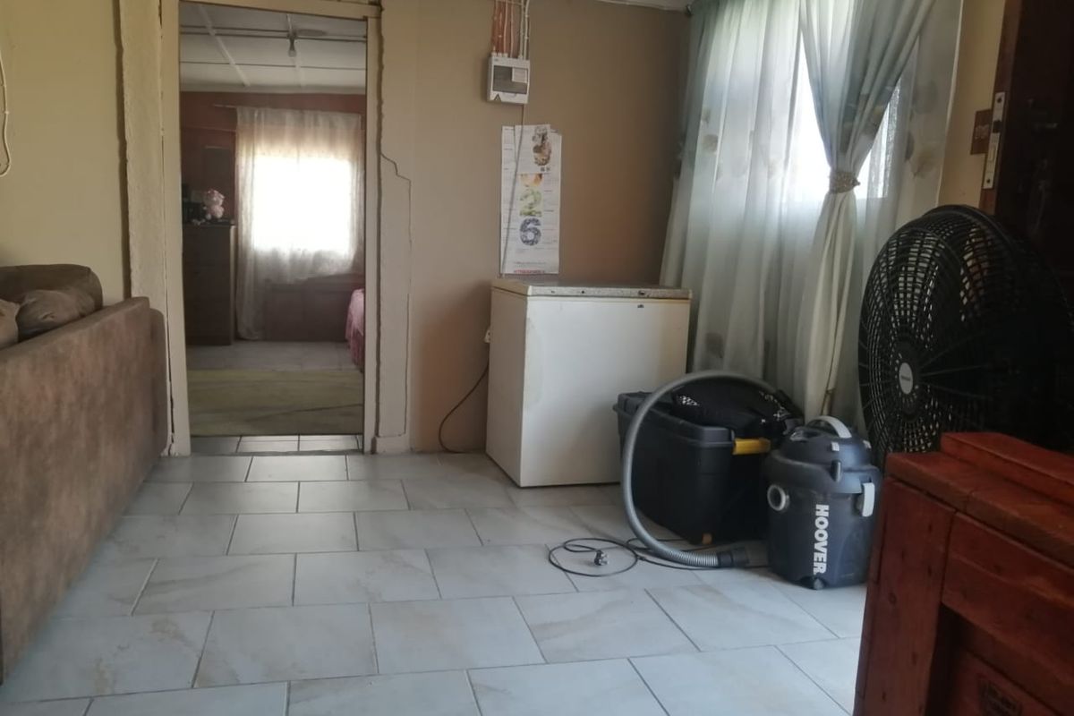 A living area featuring tiled flooring and visible wall cracks, requiring maintenance and cosmetic updates to improve the overall condition.