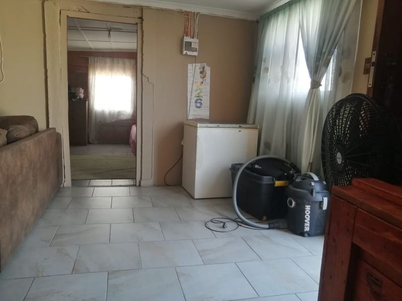 A living area featuring tiled flooring and visible wall cracks, requiring maintenance and cosmetic updates to improve the overall condition.