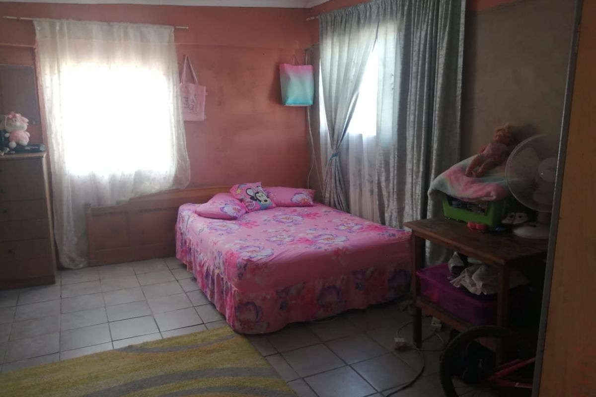 A bedroom featuring tiled flooring and dual windows with curtain rails, requiring cosmetic updates to the wall finishes.