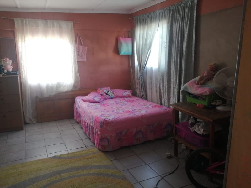 A bedroom featuring tiled flooring and dual windows with curtain rails, requiring cosmetic updates to the wall finishes.