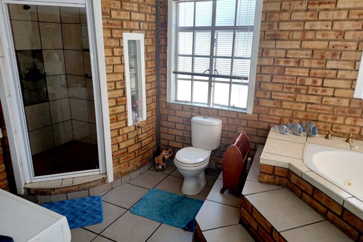 A bathroom featuring exposed brick walls, a built-in bathtub with tiled surround, a separate shower enclosure, and tiled flooring.