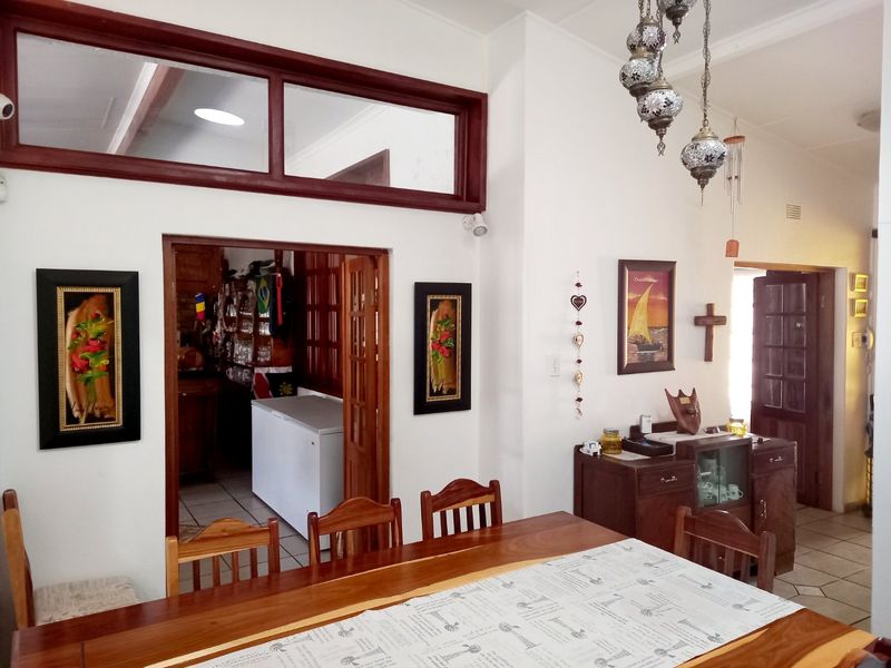 Dining room area featuring tiled flooring, wooden door frames, and a transom window, with an adjacent view into a secondary utility or kitchen space.
