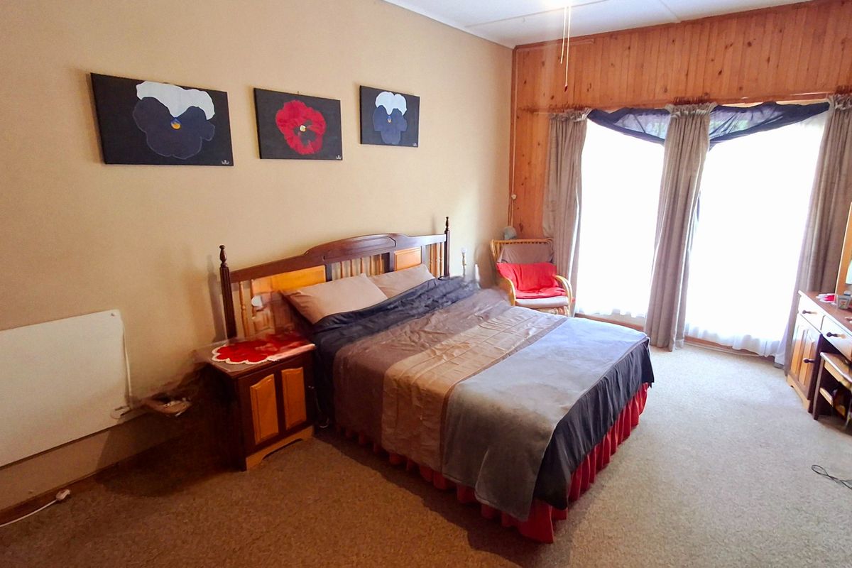A spacious bedroom featuring timber wall paneling, a wall-mounted heater, and sliding glass doors that provide natural light.