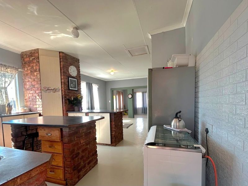 A kitchen featuring brick island bases and feature pillars, with laminate countertops and faux brick wall cladding, offering a rustic, open-plan layout.
