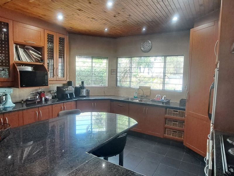 Spacious kitchen featuring timber ceilings, granite countertops, ample wooden cabinetry, and a functional layout with an integrated electric hob and extractor fan.