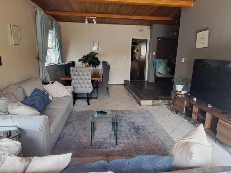 Open plan living and dining area featuring a timber ceiling, tiled flooring, and a fireplace, creating a functional and connected living space.