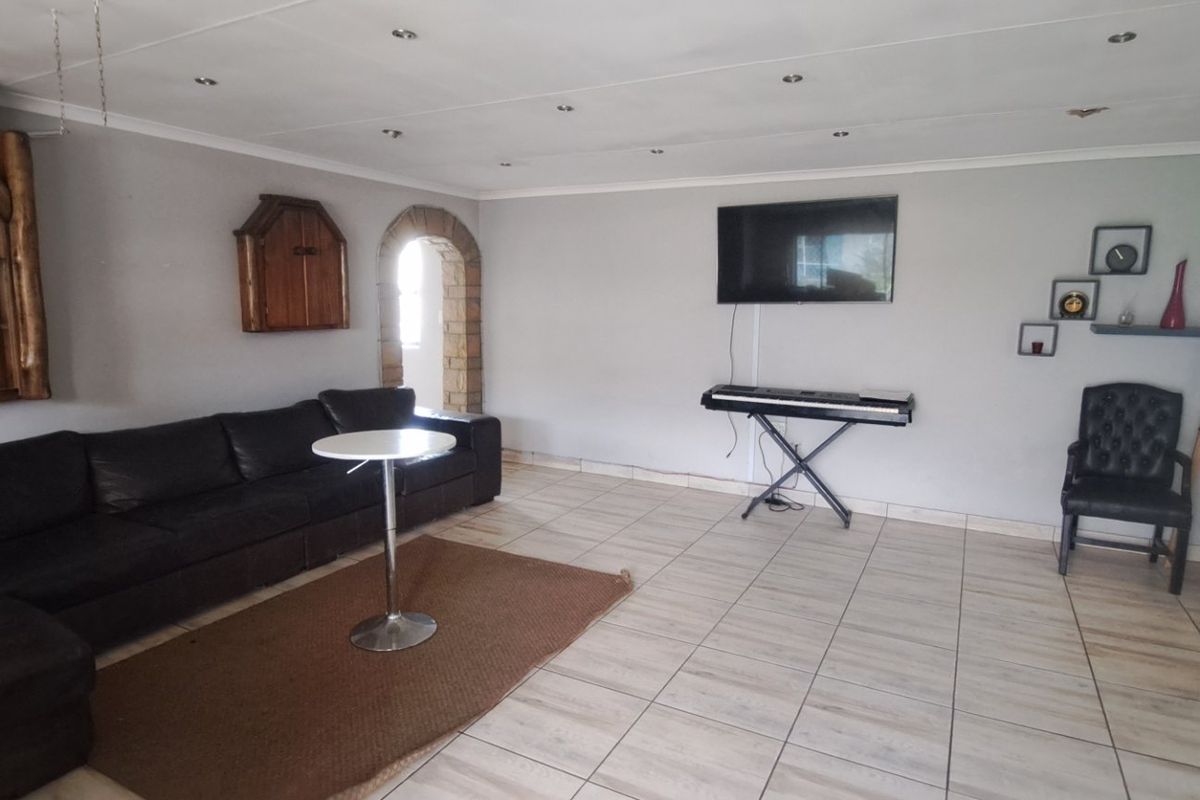 Spacious living area featuring tiled flooring, recessed downlighting, and a distinctive stone-accented archway leading to adjacent spaces.