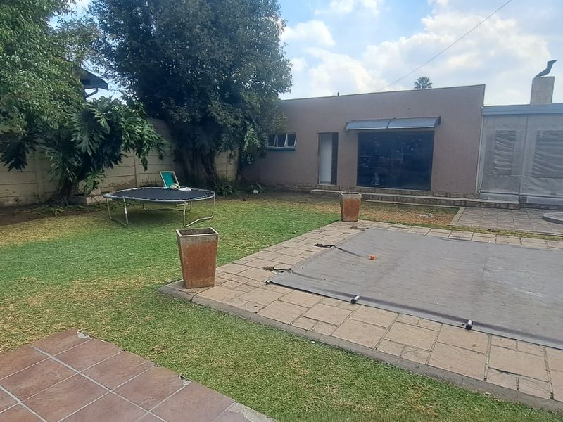 Rear garden area featuring a swimming pool with cover, paved patio space, and boundary walling.