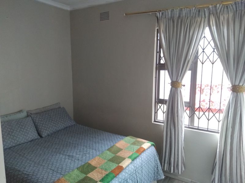 A standard bedroom featuring a window with a security gate and neutral wall finishes.