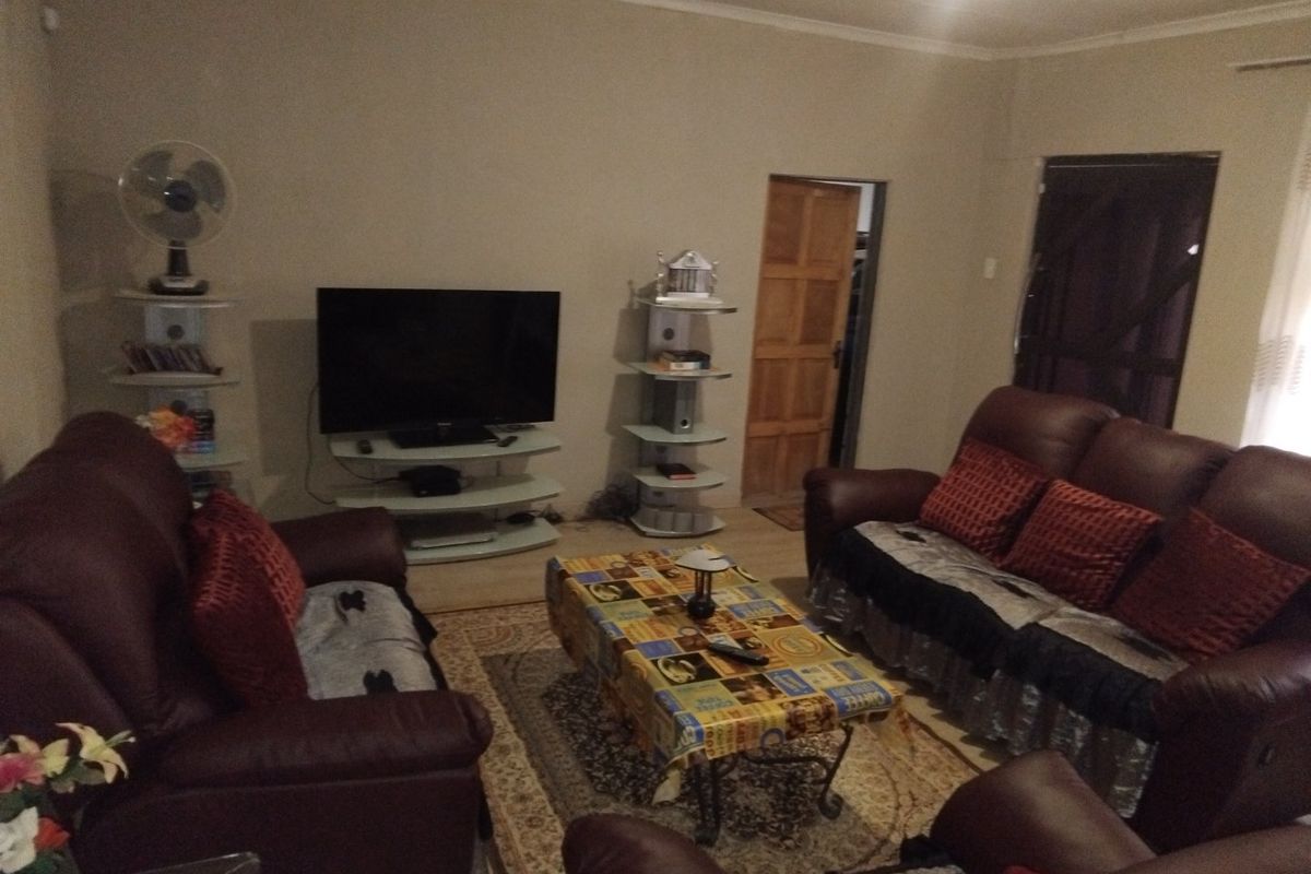 A standard living room featuring neutral wall tones, coved ceiling detailing, and a wooden internal door.