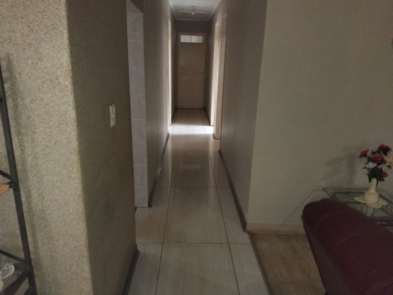 A functional interior hallway featuring tiled flooring and access to multiple rooms, providing a clean and neutral transition space within the home.