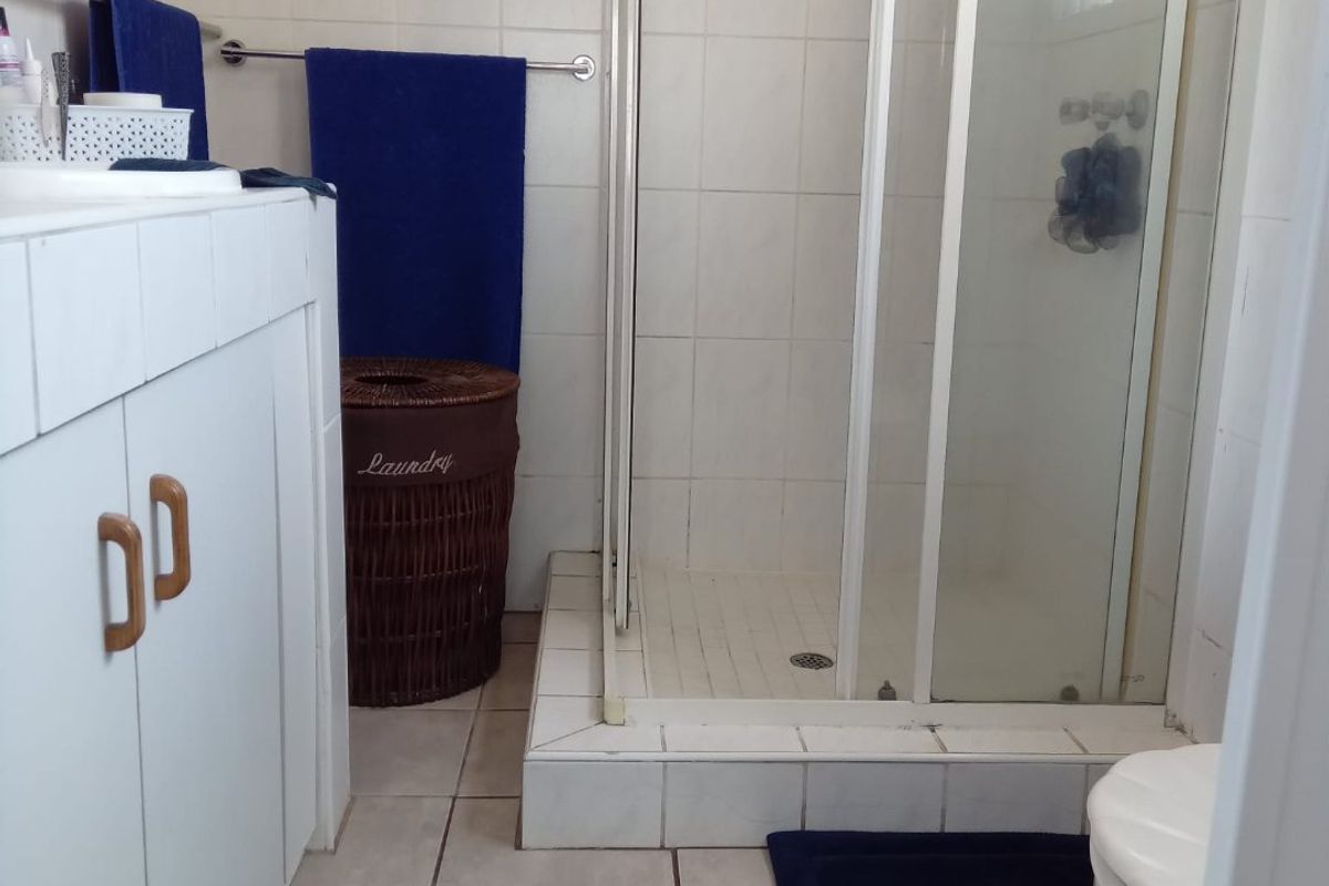 A functional bathroom featuring a shower enclosure, vanity cabinet with storage, and tiled finishes throughout.