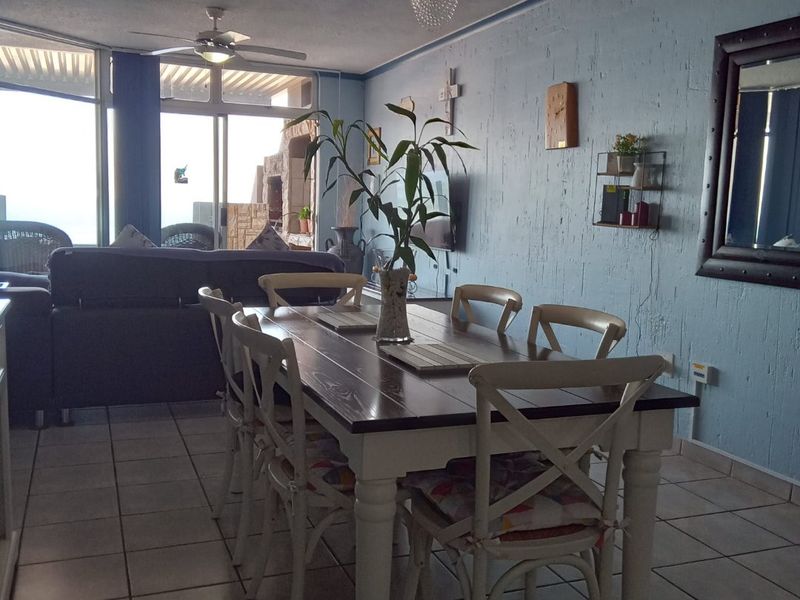 Open plan dining area featuring ceramic floor tiles, textured blue walls, and sliding glass doors leading to an outdoor patio space.