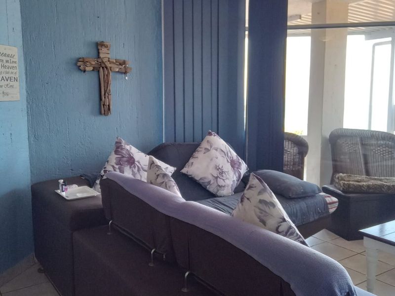 A living room area featuring textured blue walls, tiled flooring, and vertical blinds leading to an adjacent patio space.