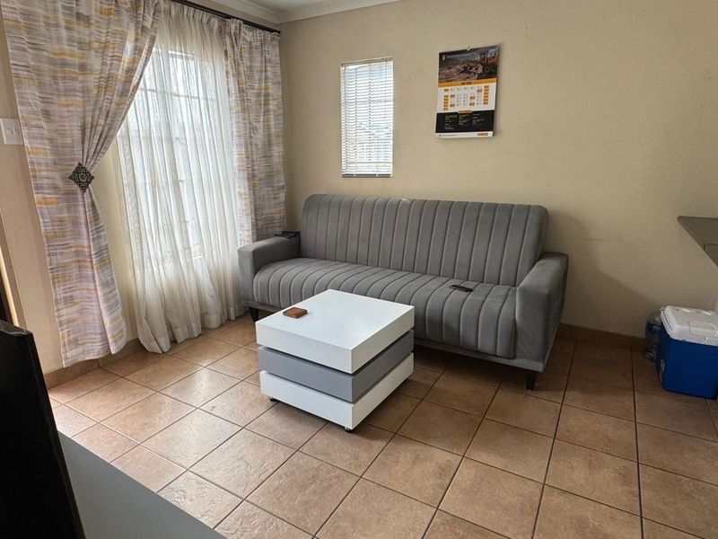 A functional living room featuring tiled flooring, window treatments, and a built-in shelf, offering a neutral base for personalization.