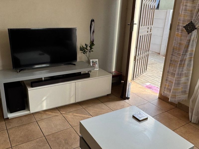 A living room area featuring ceramic floor tiles and direct access to an outdoor space through a security gate.
