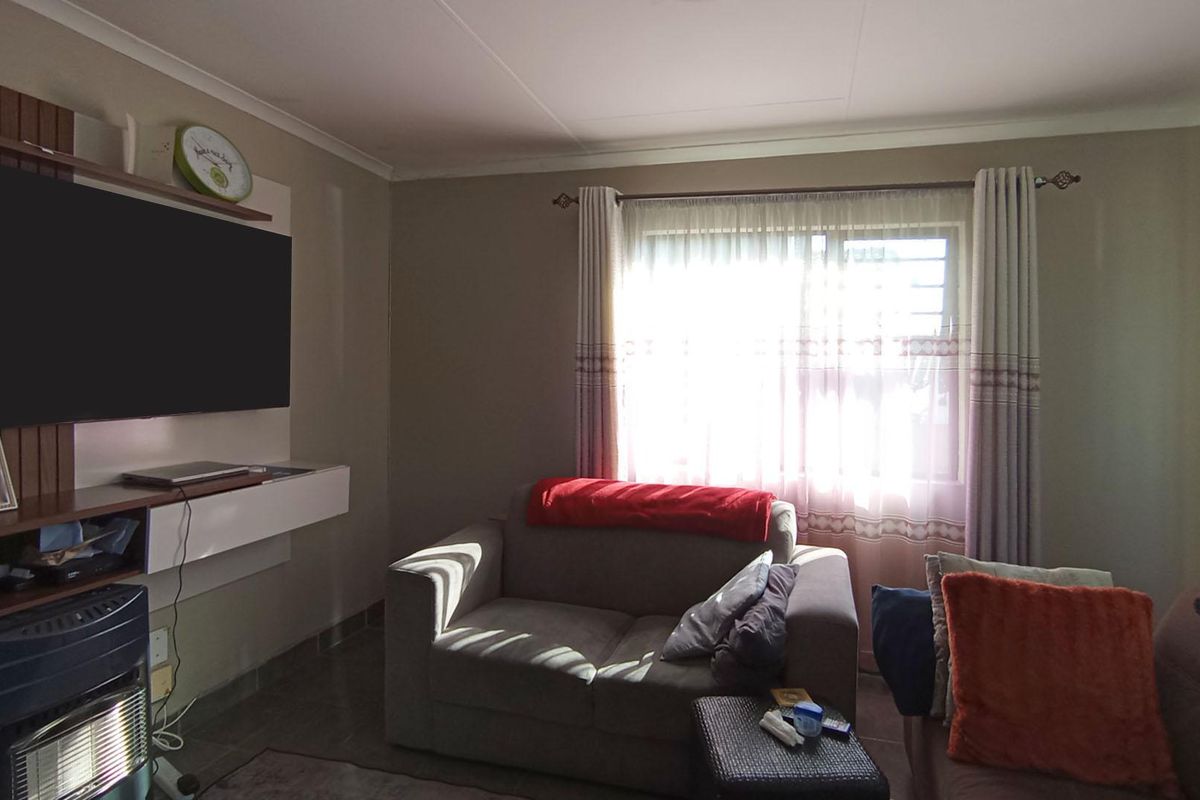 A comfortable living room featuring tiled flooring, coved ceilings, and a built-in media unit, providing a functional space for relaxation.