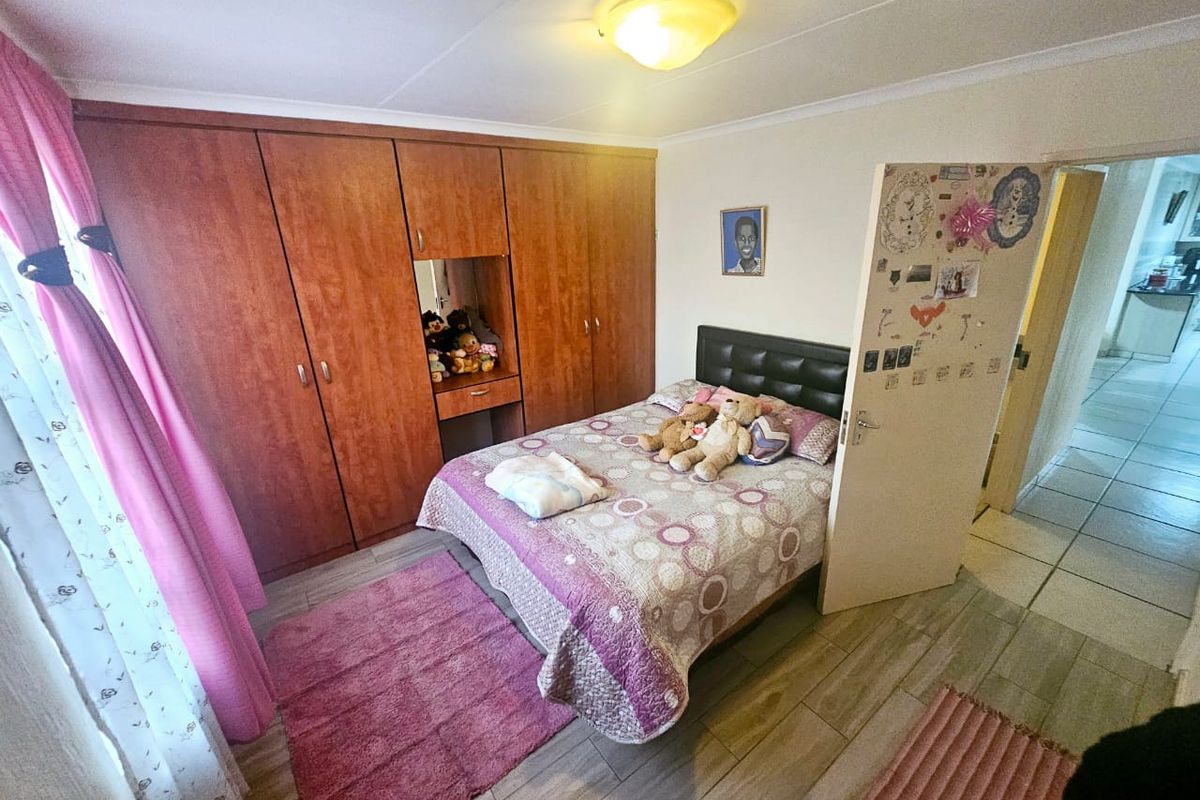 A bedroom featuring built-in wooden cupboards and tiled flooring, offering a functional space with standard finishes.