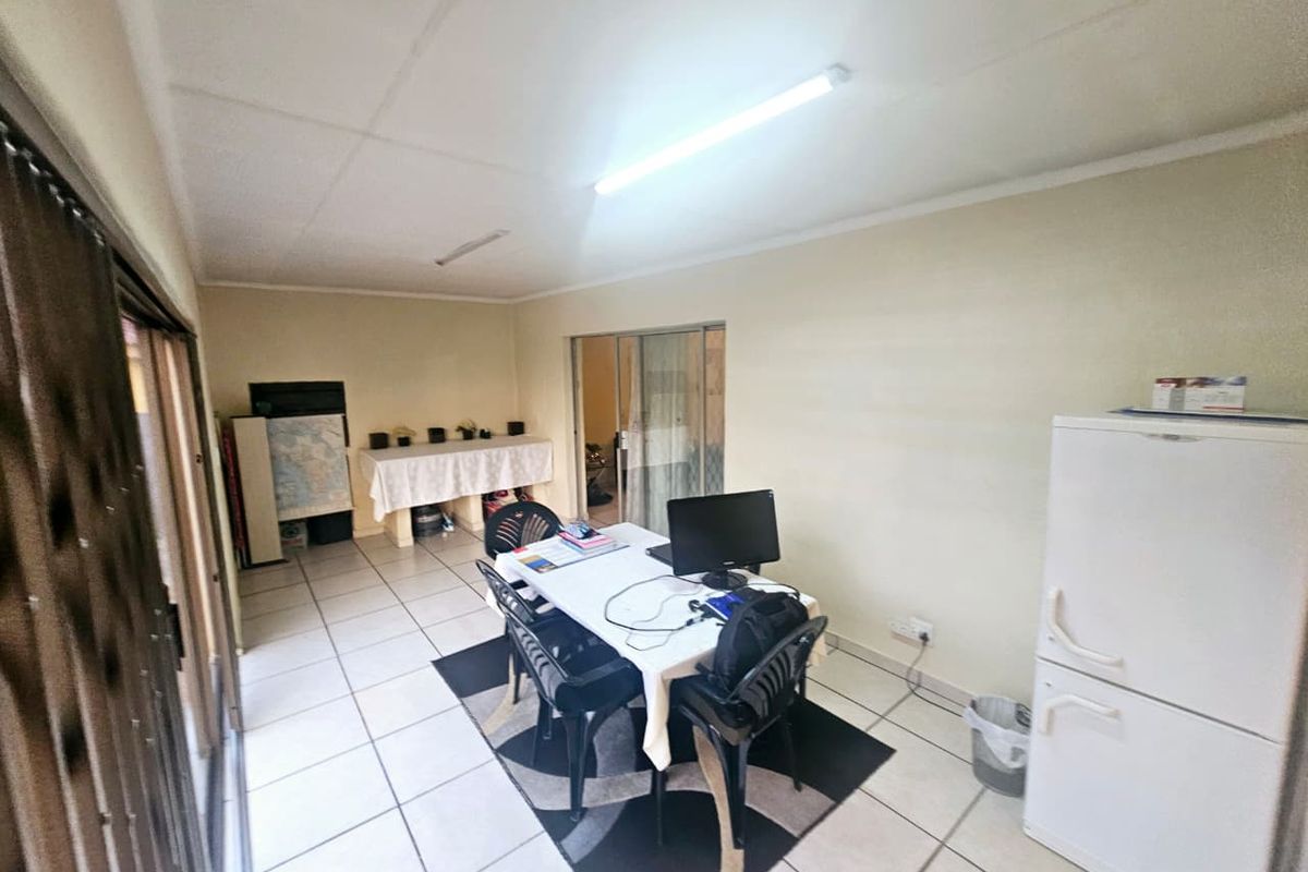 A functional living area featuring tiled flooring, sliding glass doors for natural light, and basic overhead lighting.
