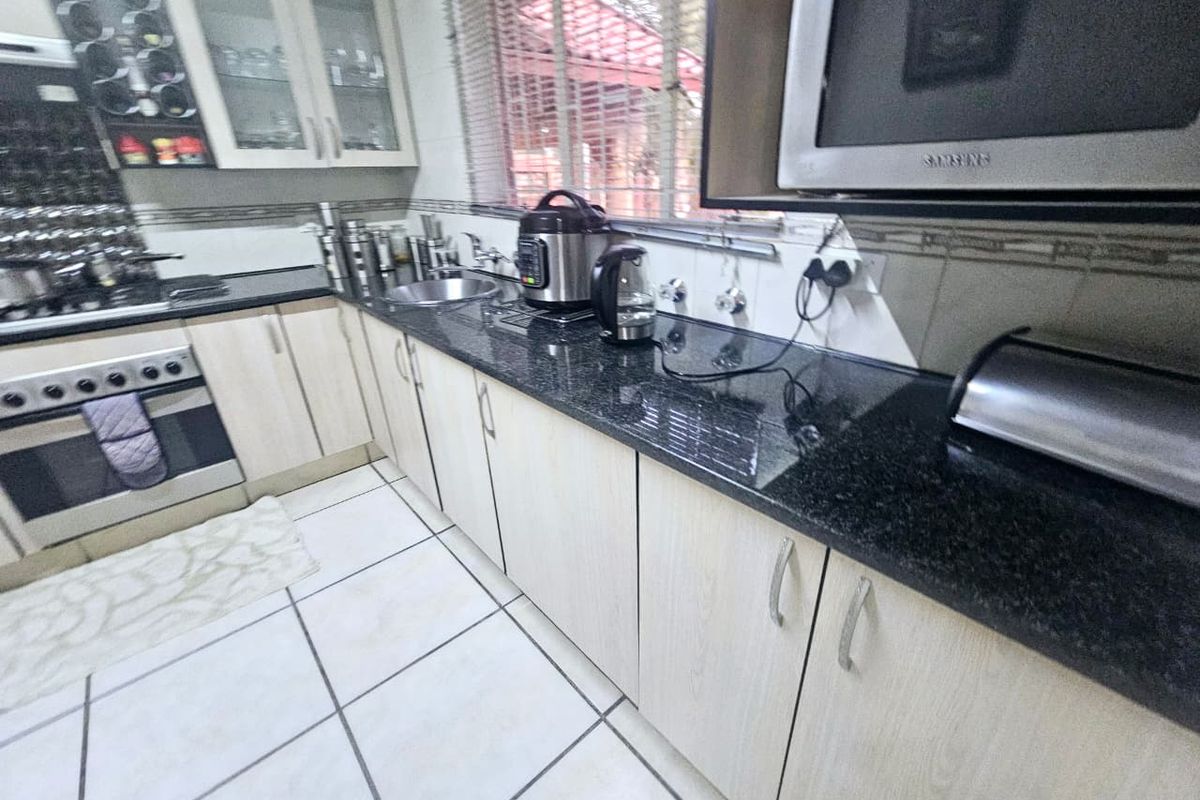 A functional kitchen featuring granite countertops, light wood-finish cabinetry, built-in oven, and tiled flooring, providing a practical workspace for daily cooking.