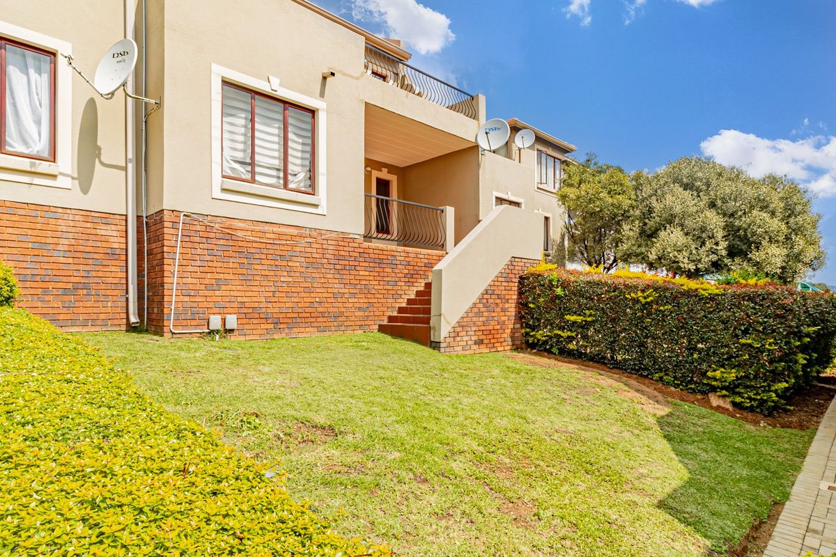 Rear view of the townhouse featuring a brick and plaster facade, an external staircase leading to a balcony, and a private garden area.