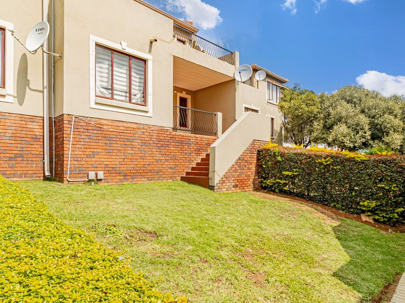 Rear view of the townhouse featuring a brick and plaster facade, an external staircase leading to a balcony, and a private garden area.