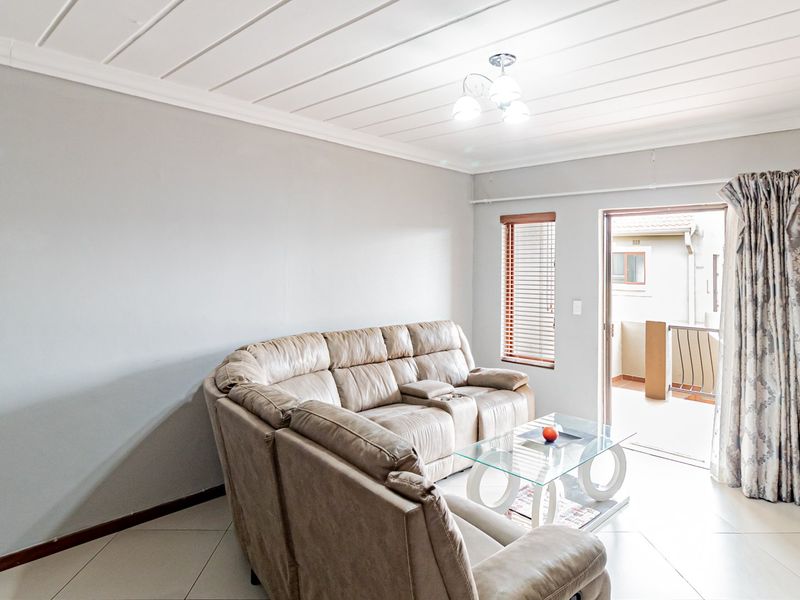 A bright living room featuring tiled flooring, a tongue and groove ceiling, and direct access to an outdoor patio area through a sliding door.