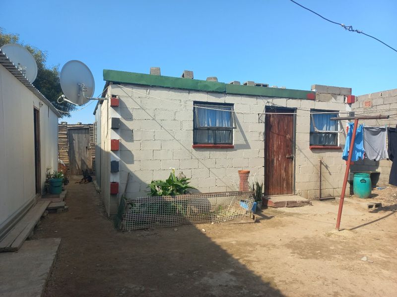 Rear view of a single-story concrete block dwelling featuring a satellite dish and basic exterior finishes.