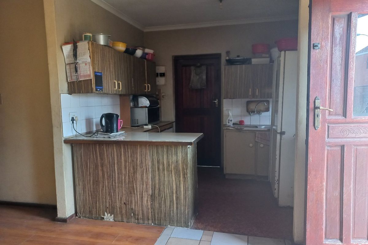 A dated kitchen featuring laminate cabinetry, tiled backsplash, and a breakfast counter, requiring modernization to improve functionality and aesthetic appeal.