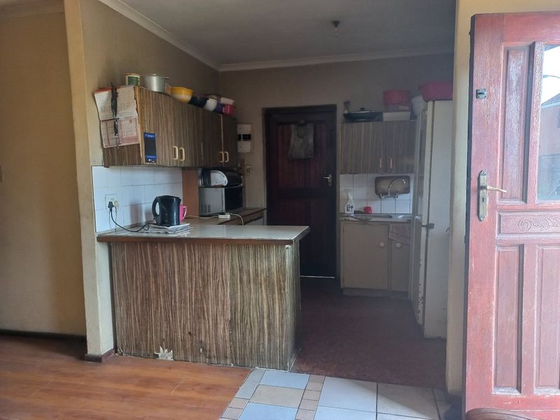 A dated kitchen featuring laminate cabinetry, tiled backsplash, and a breakfast counter, requiring modernization to improve functionality and aesthetic appeal.