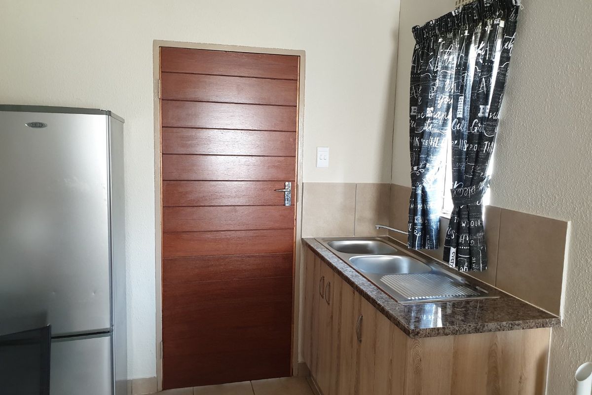A functional kitchen area featuring a double bowl stainless steel sink, granite countertops, and wood-finish cabinetry.