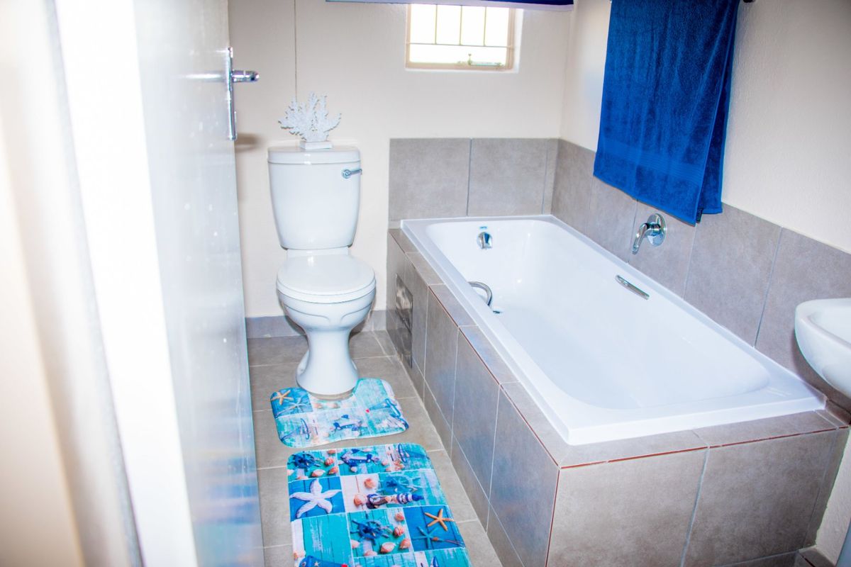 A functional bathroom featuring a bathtub with tiled surround, a standard toilet, and a wall-mounted basin.